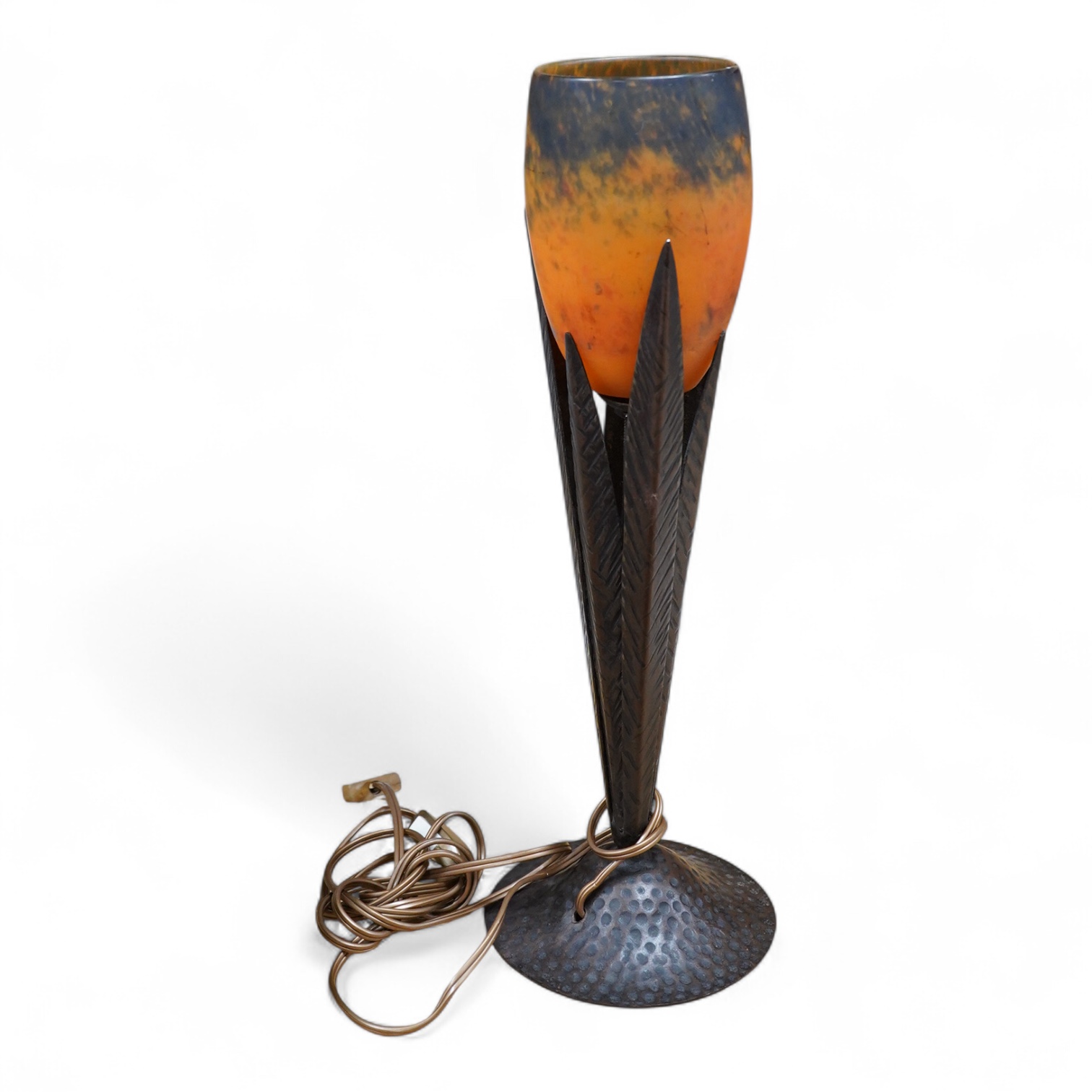 Manner of Muller Freres and Robj: A French Art Deco table lamp the mottled orange glass shade supported by naturalistic palm-leaf metal supports terminating in a circular hammered metal base, 40cm high
